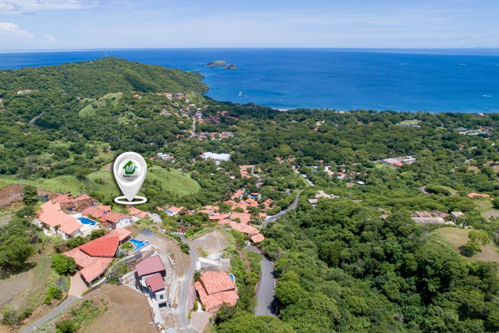 Aerial view of a coastal town with lush greenery and ocean in the background.