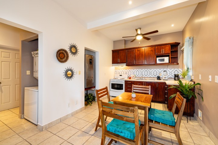 Modern kitchen with wooden cabinets, tile flooring, table, chairs, and decorative wall accents.