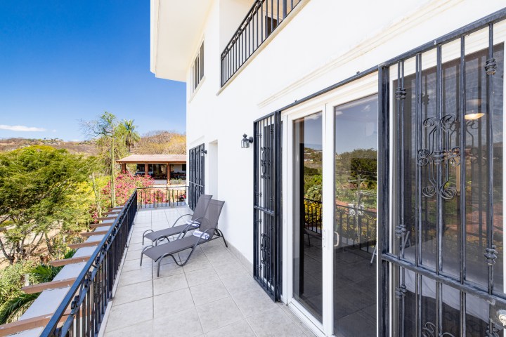 Sunny balcony with lounge chairs and mountain view on a clear day.