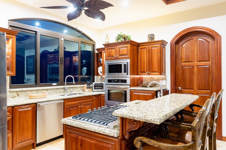 Modern kitchen with wooden cabinets, granite countertops, and stainless steel appliances.