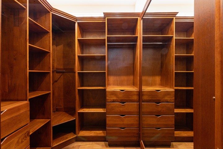 Spacious wooden wardrobe with shelves and drawers, empty and well-lit.