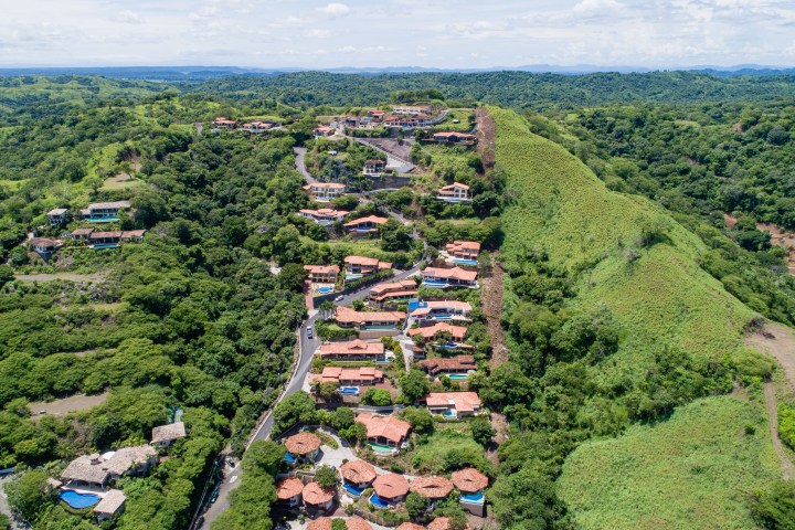 Aerial view of hillside houses with red roofs and green landscape.