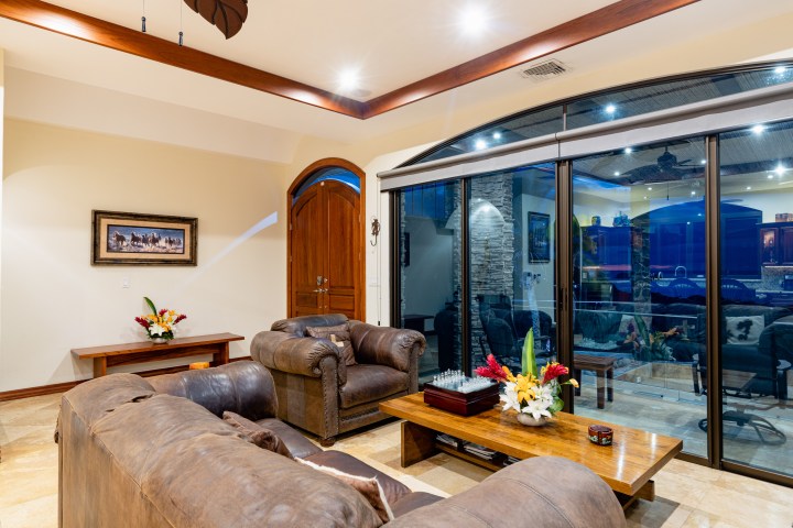 Living room with leather sofas, wooden table, sliding glass doors, and wall art.