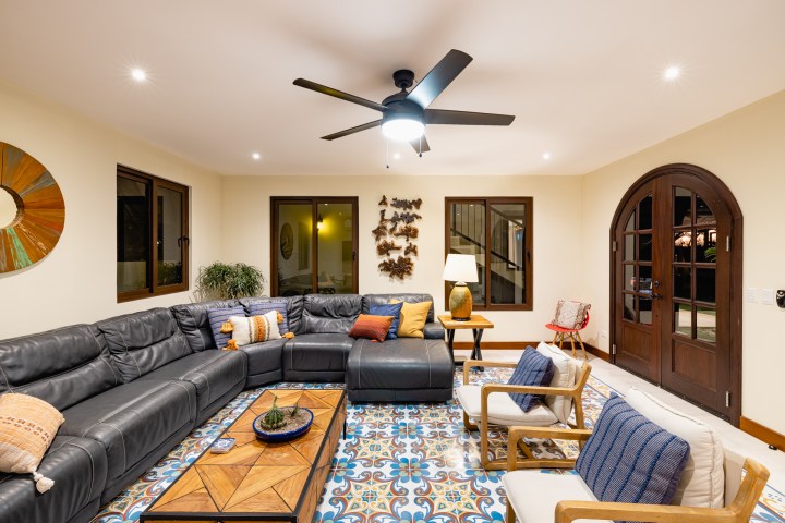 Cozy living room with sectional sofa, patterned floor tiles, modern decor, and ceiling fan.
