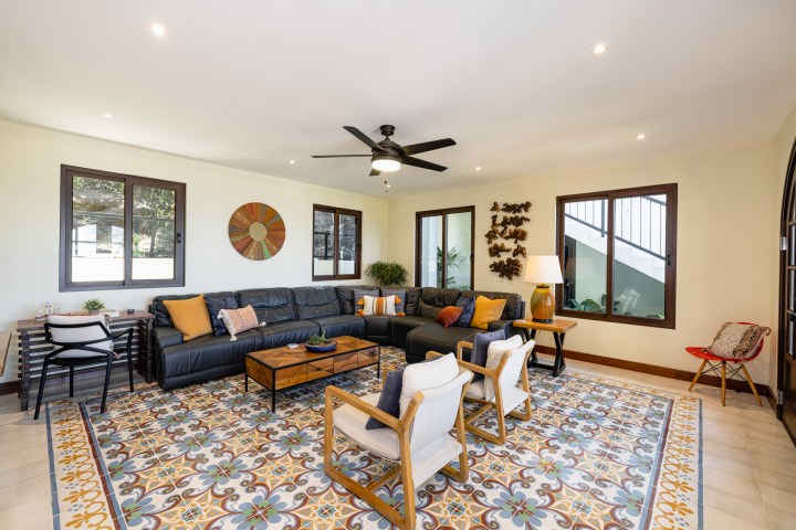 Living room with sectional sofa, colorful cushions, patterned rug, and wall decor.