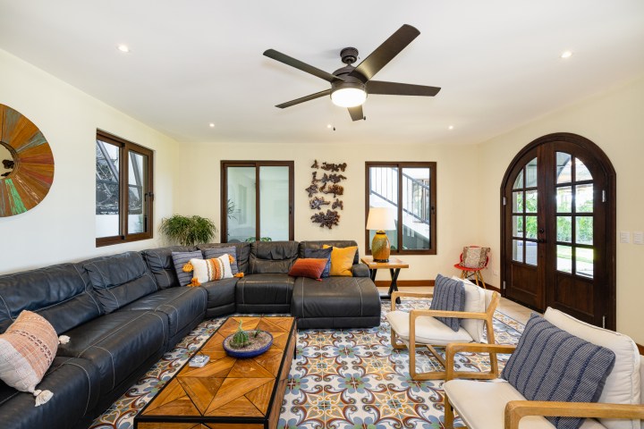 Cozy living room with sectional sofa, patterned rug, and ceiling fan.