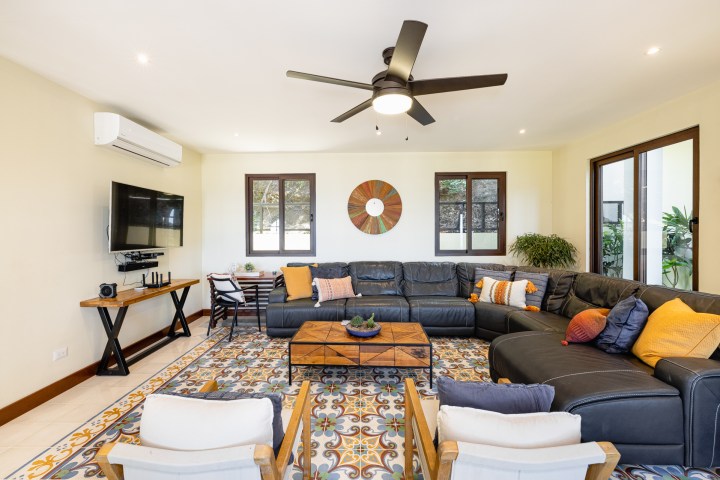 Spacious living room with sectional sofa, TV, ceiling fan, and colorful decor.