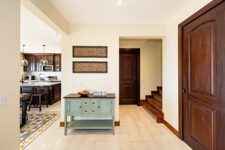 Interior with wooden doors, kitchen view, staircase, and a green console table