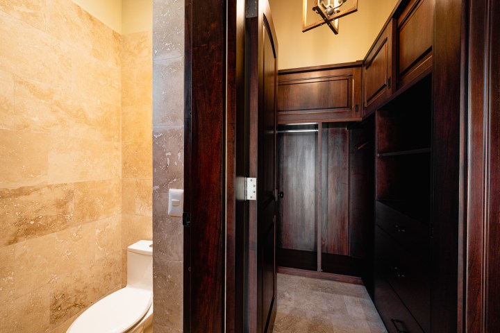 Bathroom with stone walls and adjoining dark wood wardrobe.