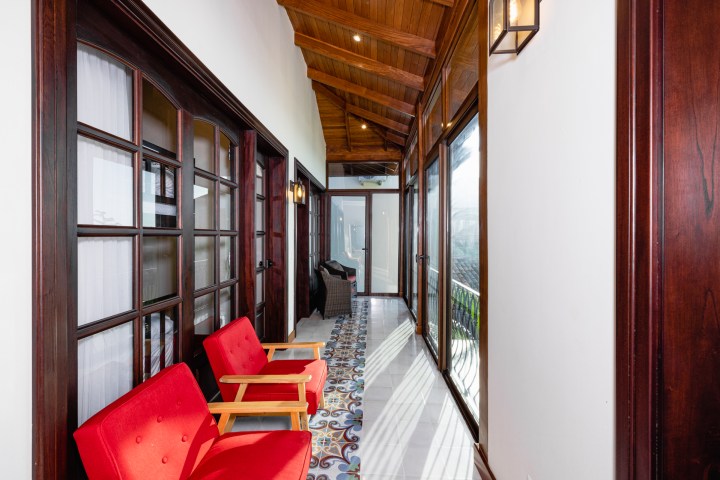 Wood-accented hallway with red chairs and patterned tile floor, leading to a glass door.