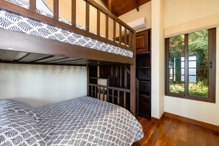 Room with wooden bunk bed, window with garden view, and patterned bedding.