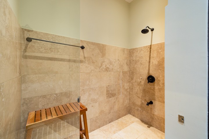 Tile shower with bench, wall-mounted showerhead, and towel bar.
