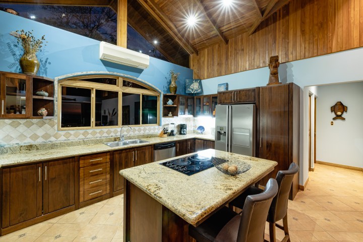 Modern kitchen with granite countertops, wooden cabinets, island, and stainless steel appliances.