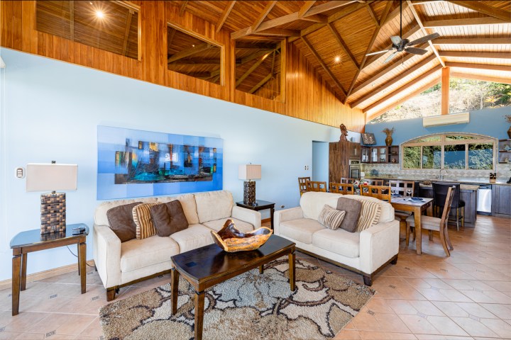Spacious living room with wooden ceiling, sofas, and dining area.