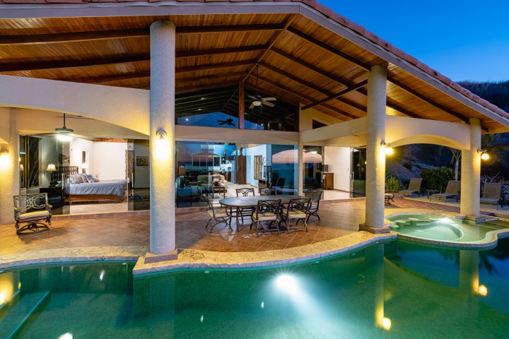 Luxurious open-air patio with swimming pool, jacuzzi, and seating area at dusk.