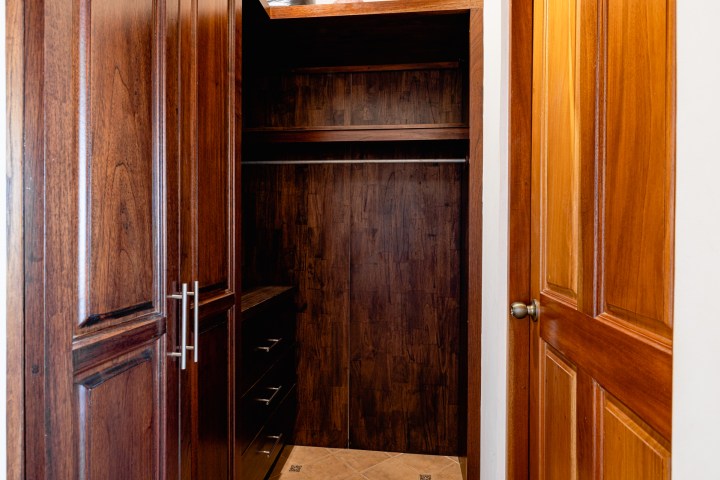 Open wooden closet with empty shelves and drawers inside.