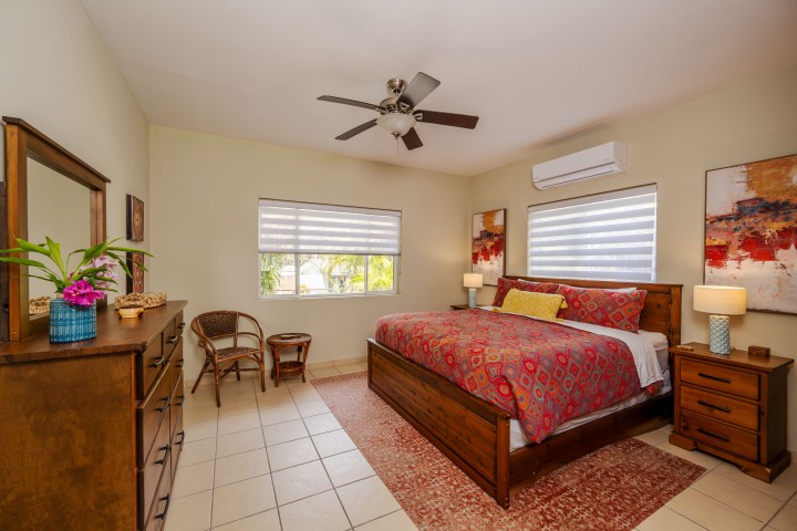 Cozy bedroom with wooden furniture, colorful bedding, and a ceiling fan.