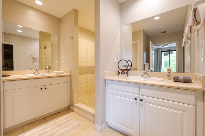 Bathroom with two sinks, mirrors, and a central walk-in shower.
