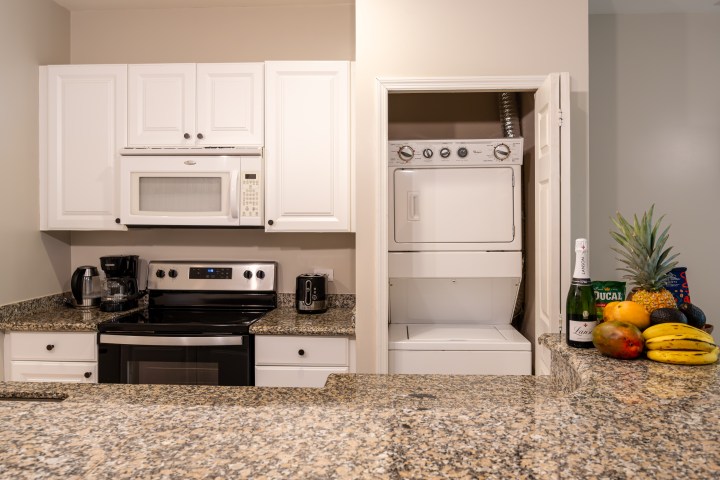 Kitchen with granite countertops, white cabinets, and a stackable washer-dryer.