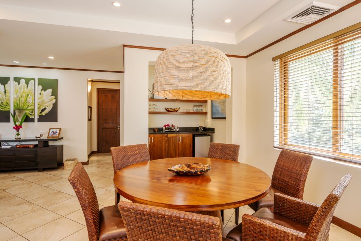 Cozy dining room with round wooden table, wicker chairs, and a large wicker pendant light.