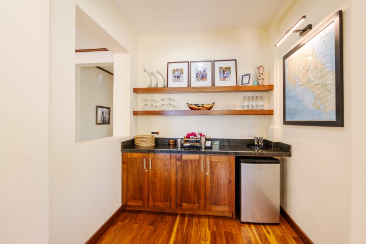 Wooden kitchenette with shelves, map on wall, and mini fridge.