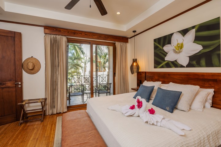 Bedroom with large bed, art on wall, sliding doors, and palm view.