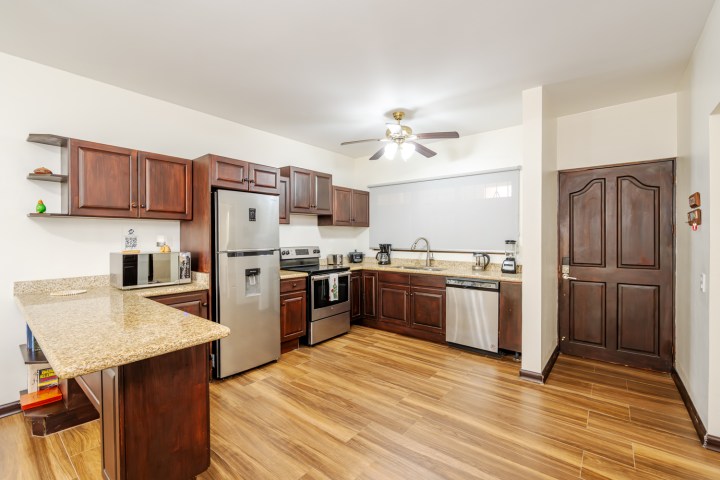 Modern kitchen with wooden cabinets, stainless steel appliances, and a ceiling fan.