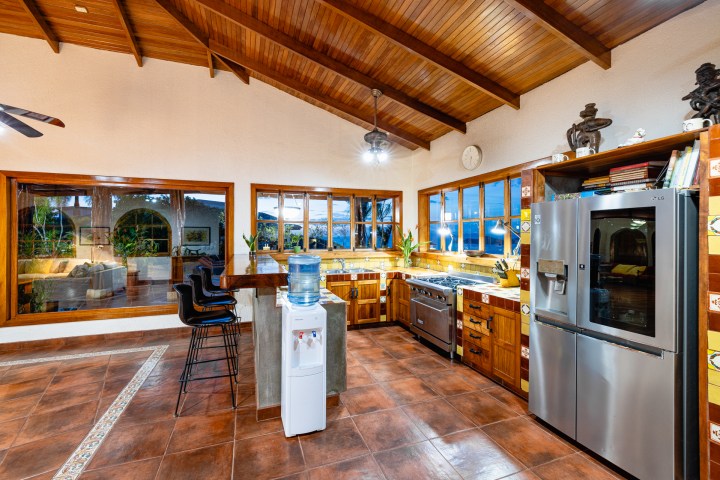 Spacious kitchen with wood cabinets, stainless appliances, and large windows at night.