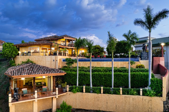 Luxurious villa with palm trees and swimming pool at sunset.