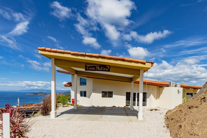 Modern house with tiled roof, ocean view, and clear sky in the background.