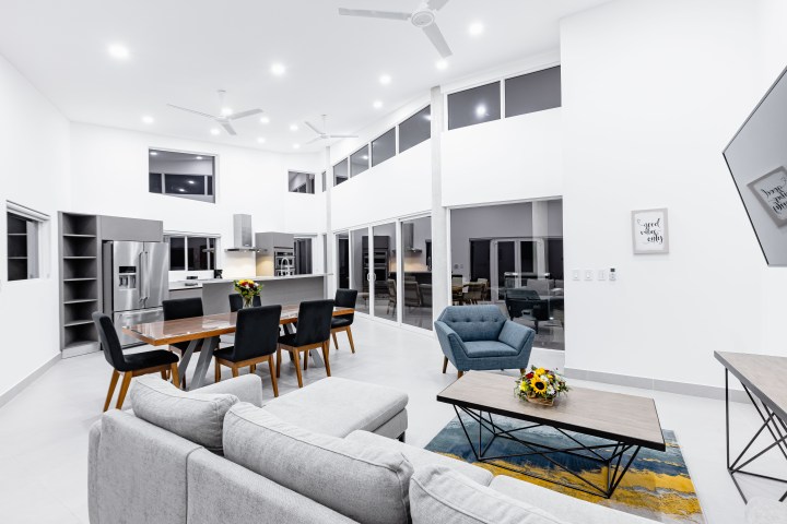 Modern open-plan living room and kitchen with white walls and high ceilings.