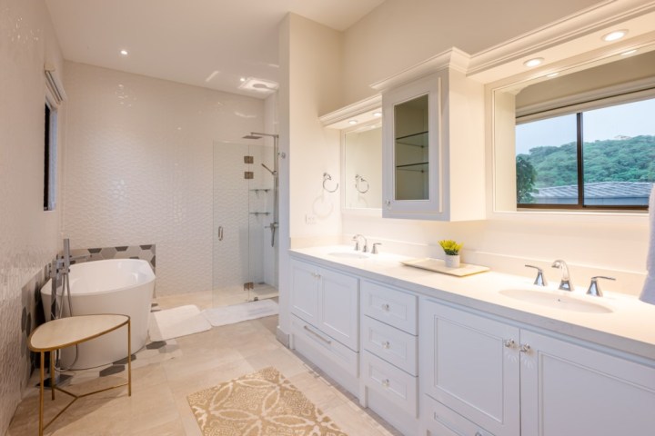 Modern bathroom with freestanding tub, glass shower, double vanity, and window.