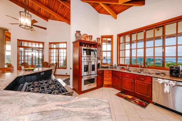 Spacious kitchen with wooden cabinets, stainless steel appliances, and large windows overlooking a scenic view.