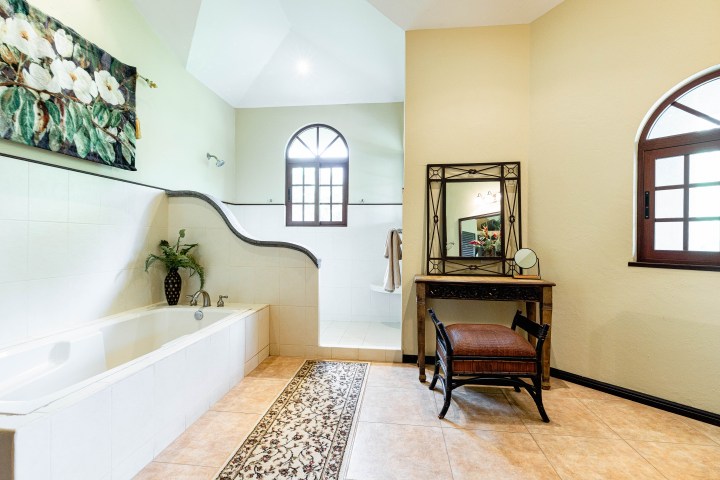 Spacious bathroom with bathtub, art, vanity, and window.