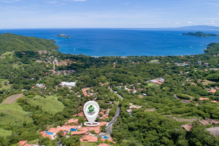 Aerial view of a coastal town with lush greenery and ocean.