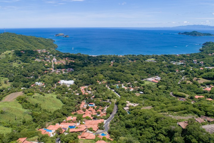 Aerial view of a coastal village with lush greenery and ocean.