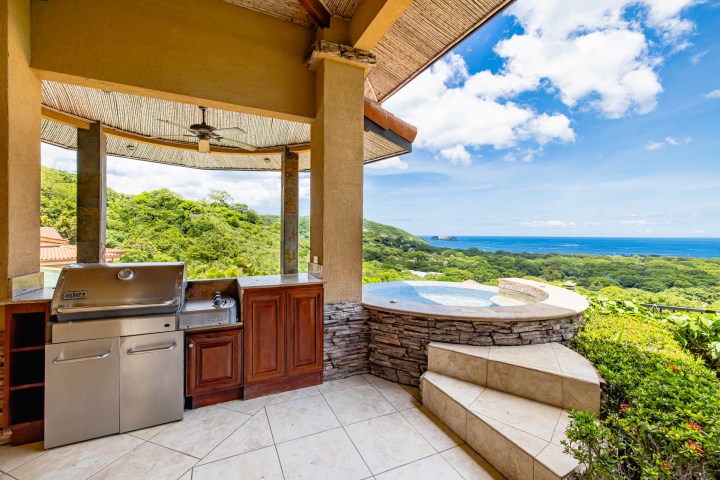 Outdoor kitchen with grill, sink, and ocean view.
