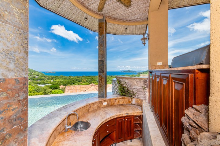 Outdoor bar with ocean view and curved countertop.