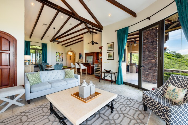 Spacious living room with modern furniture, large windows, and exposed beams.