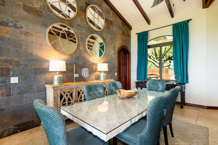 Elegant dining room with mirrored wall, blue chairs, and glass table.
