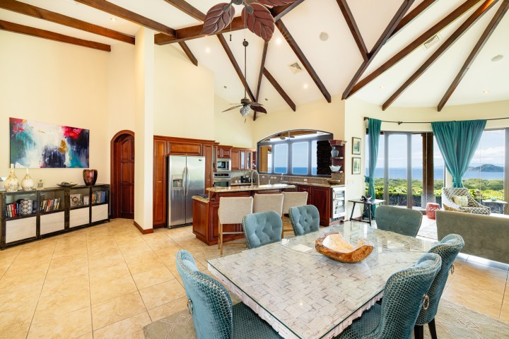 Spacious, elegant living room with ocean view, high wooden beams, and modern furniture.