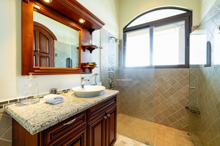 Elegant bathroom with granite vanity, vessel sink, and large glass shower.