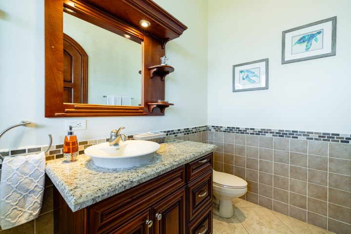 Bathroom with granite sink, wooden cabinet, and toilet.