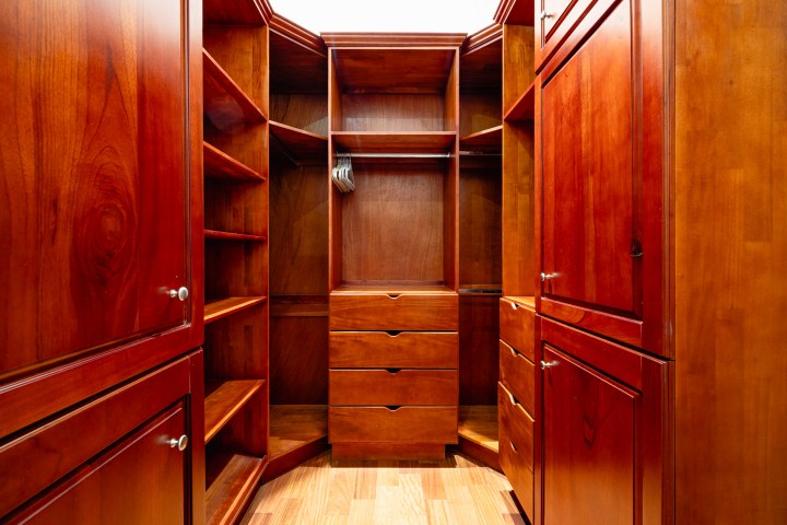 Wooden walk-in closet with shelves and drawers.