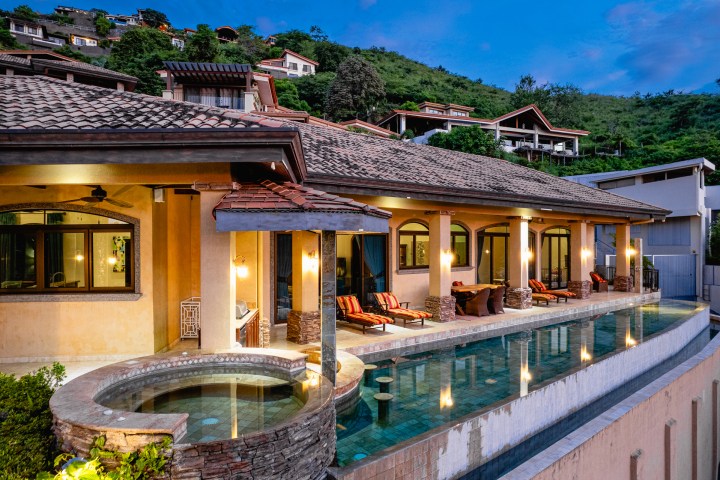Luxurious villa with pool and hillside view at dusk.
