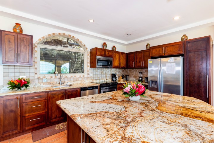 Kitchen with granite countertops, wooden cabinets, stainless steel appliances, and floral arrangements.