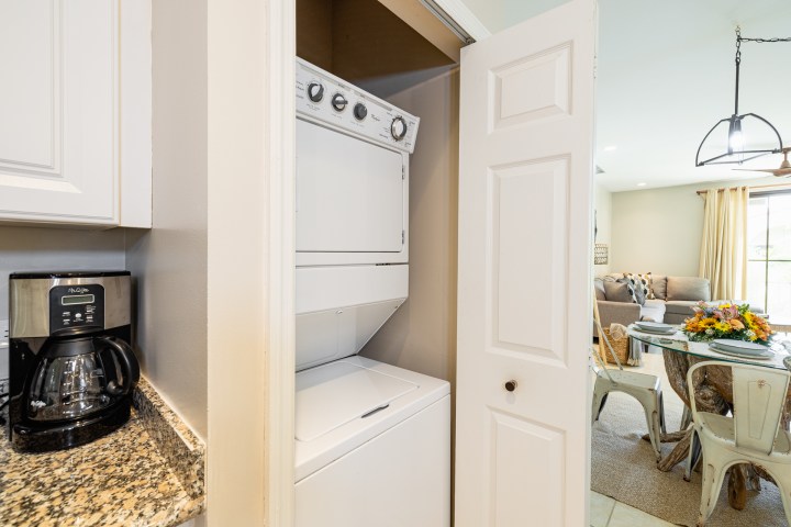 Compact laundry area with stacked washer and dryer next to kitchen counter and coffee maker.