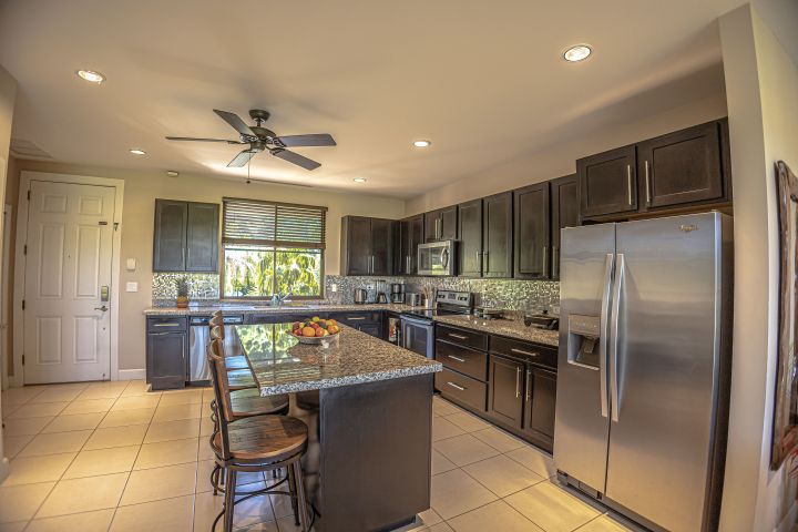 Modern kitchen with dark cabinets, granite countertops, and stainless steel appliances.