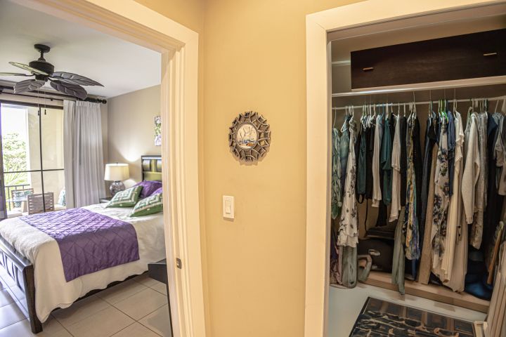 Room view with open closet on right, bed with purple quilt on left.