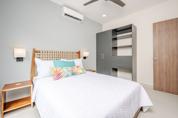 Bedroom with wooden bed, nightstand, and wardrobe on a light blue wall.